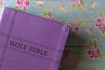 purple Bible on a floral background 