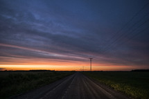 power lines along a dirt road at sunset 