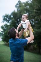 father lifting up his toddler daughter 