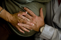 mother and father's hands on a pregnant belly
