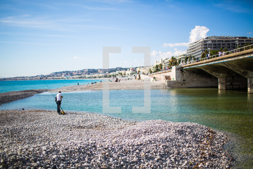 a fisherman on a rocky beach in Nice, France 
