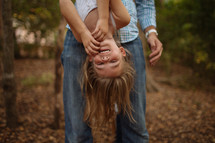 a father holding his daughter upside down 