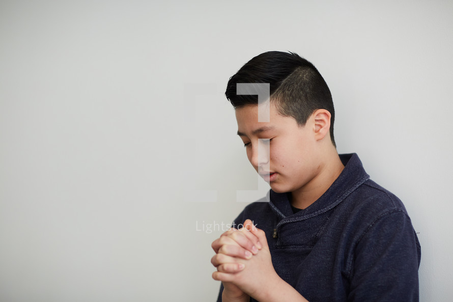 boy with head bowed in prayer