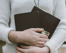 woman holding a Bible and journal close to her heart 