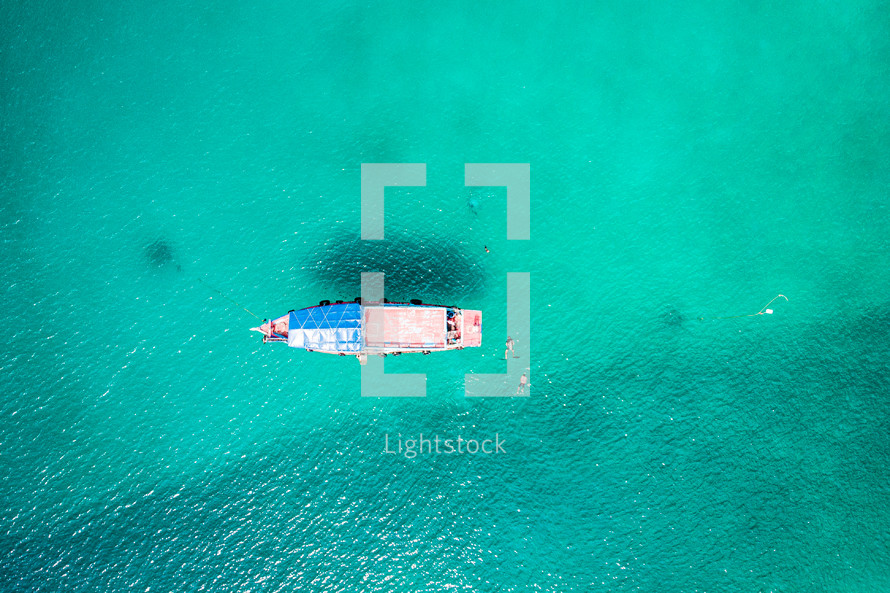 aerial view over a boat on turquoise waters 