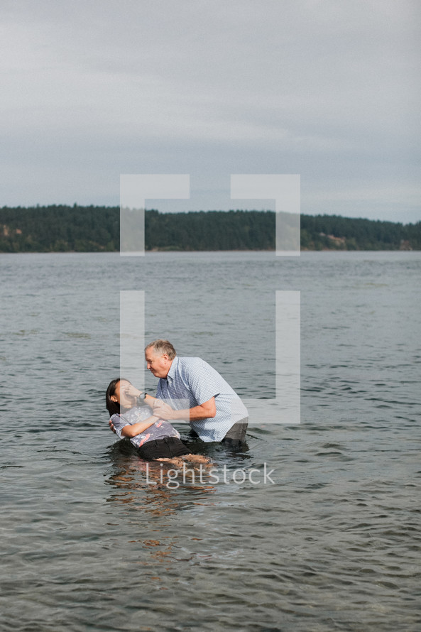 a woman being dunked in a river to be baptized 