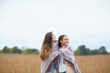 friends under a blanket standing in a field 
