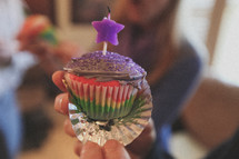 A girl holding a birthday cupcake
