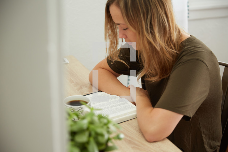 a woman reading a Bible at her desk 