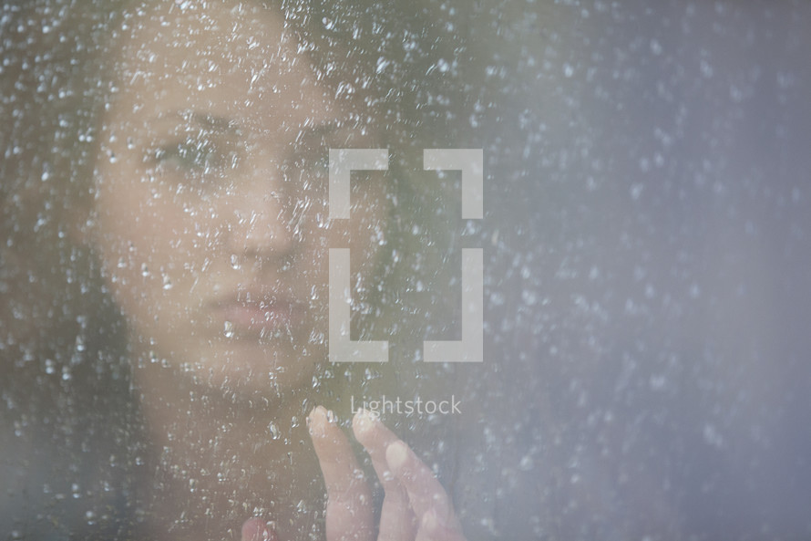 Young girl  looking out a frosted window.