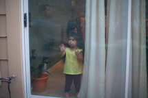 a toddler girl looking out a window 