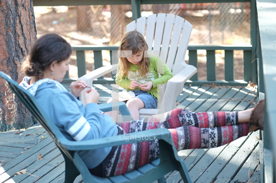 mother and daughter doing crafts on a back porch 