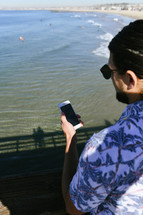 a man on a pier looking at his cellphone 