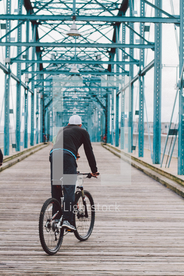 a man on a bicycle on a bridge 