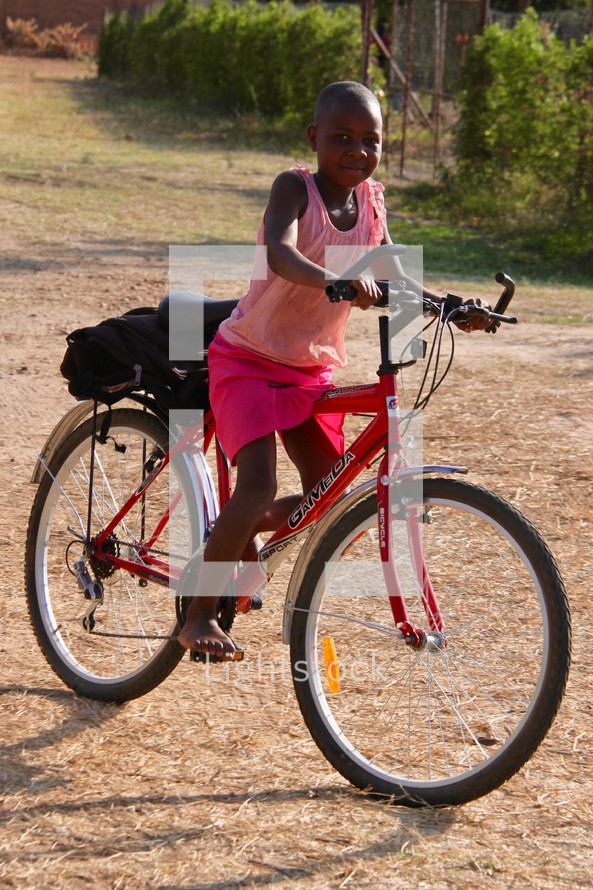 a girl riding a bicycle on a dirt road 