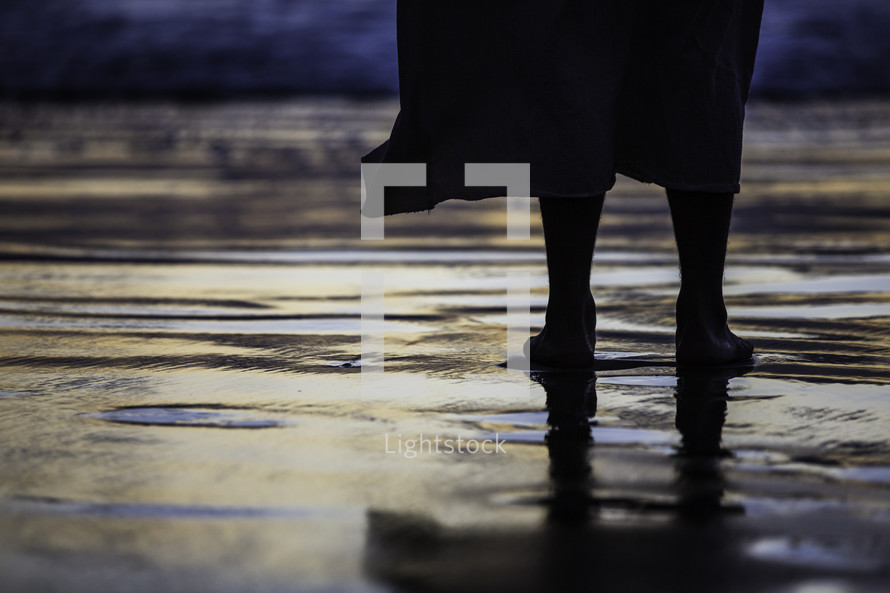 feet of Christ standing on wet sand 