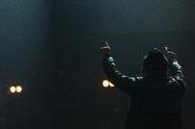 a man on stage pointing up to heaven 