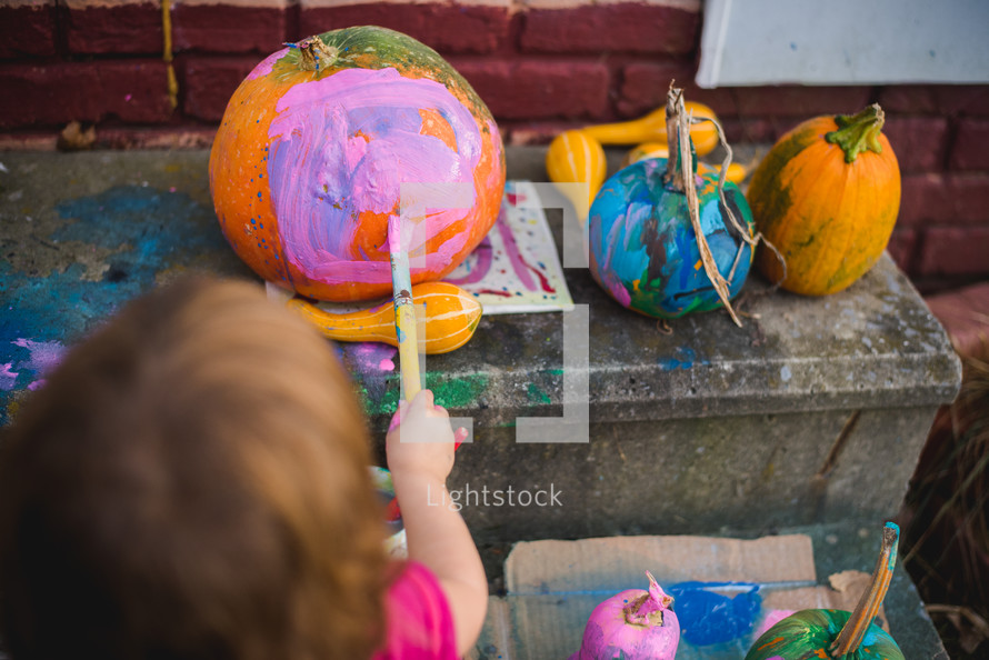kid painting a pumpkin