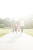 family walking outdoors holding hands together. 