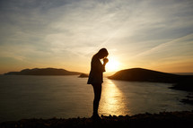a woman praying at sunset 