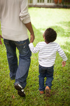 father and son walking holding hands outdoors 