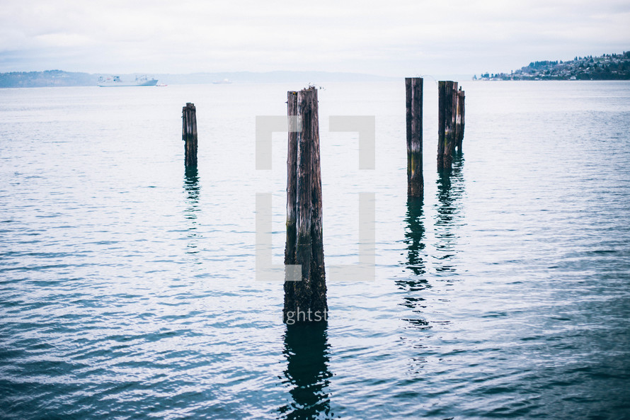 Wooden pier posts emerging from the ocean water.