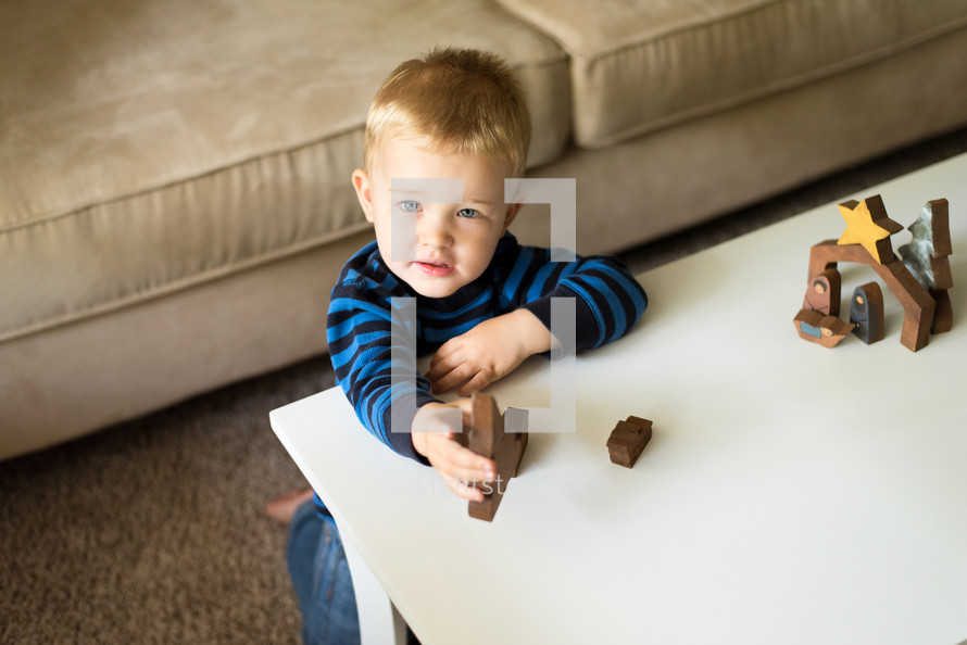 toddler playing with a wooden nativity 