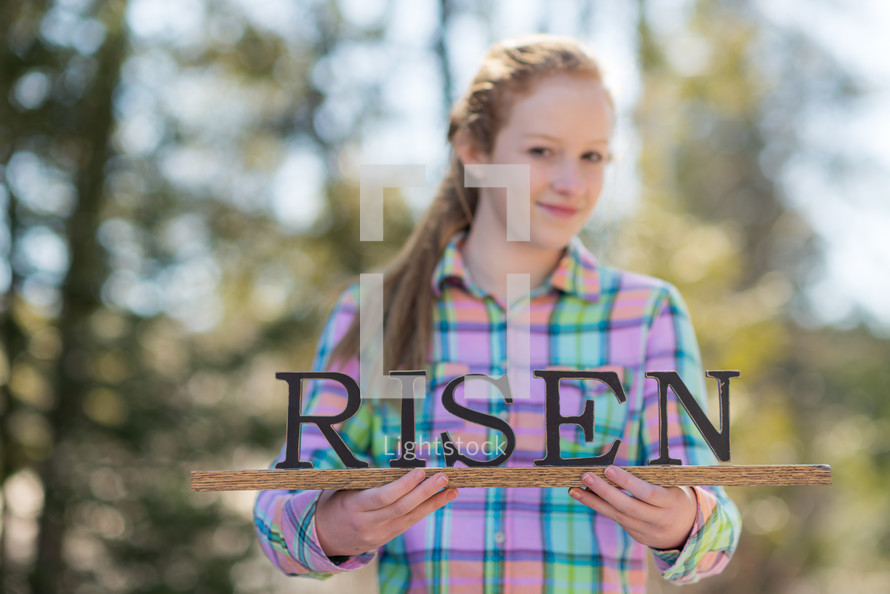 teen girl holding a Risen sign 
