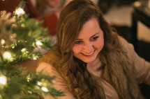 A smiling woman near a Christmas tree.