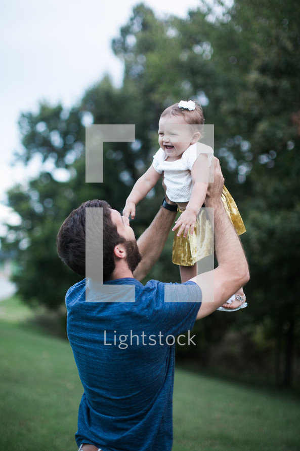 father lifting up his toddler daughter 