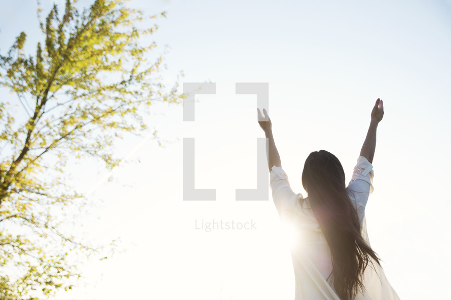 woman standing outdoors with raised arms 