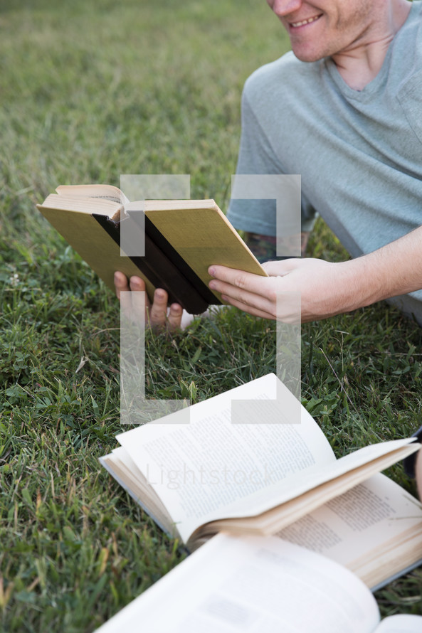 man reading a book in the grass 