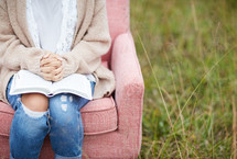 a woman sitting in a chair with praying hands over a Bible 