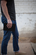 a man walking carrying a Bible