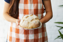 a woman holding homemade bread 