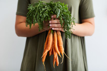 woman holding a bunch of carrots 