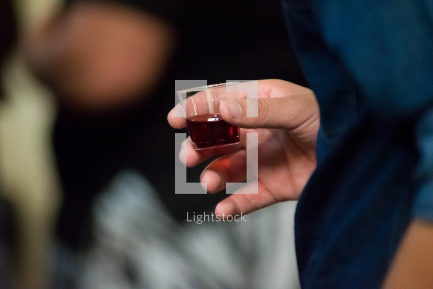 person holding a communion wine cup 