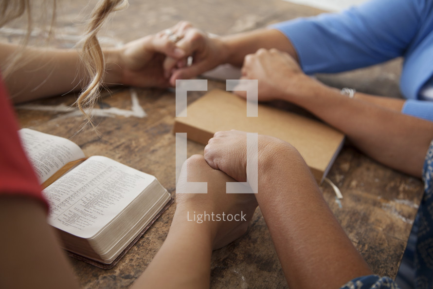 holding hands in prayer at a Bible study 
