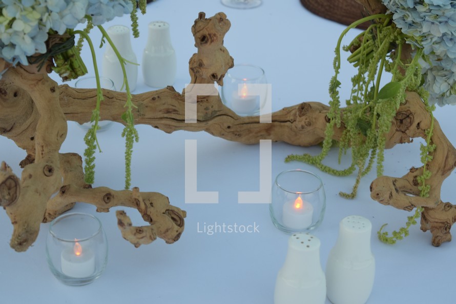 candles, driftwood, and hydrangeas as a centerpiece on a table for a beach themed wedding 