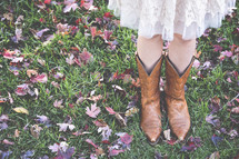 girl in cowboy boots standing in fall leaves 