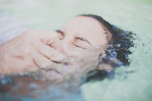 Woman being baptized in a pool of water.