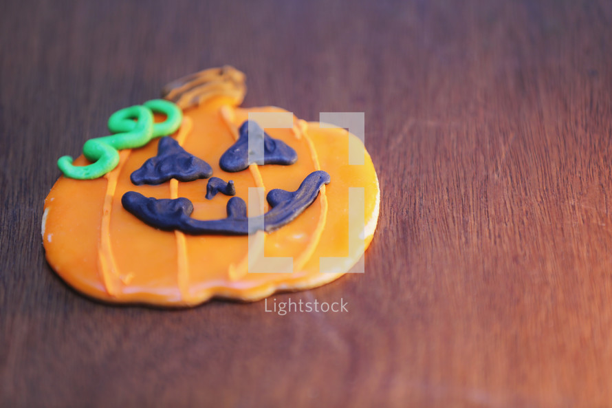 A Halloween cookie decorated like a pumpkin.