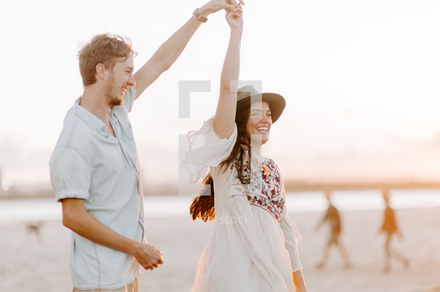 a cheerful couple dancing on a beach 
