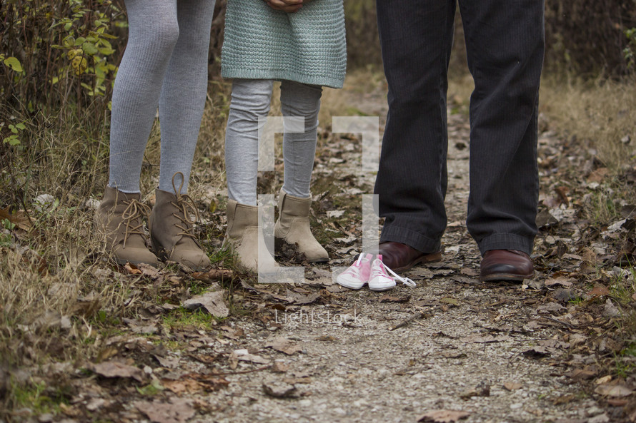 Family standing on a trail outside with a pair of baby shoes.