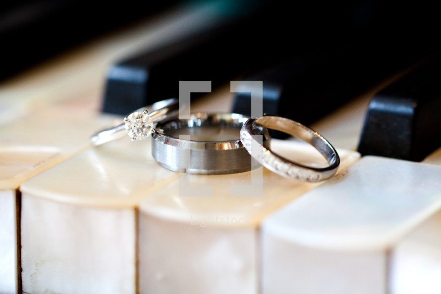 wedding bands and engagement rings on piano keys 