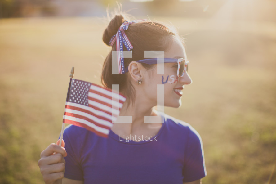 woman holding an American flag and USA face paint 