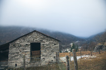 stone barn and fence on a mountainside 