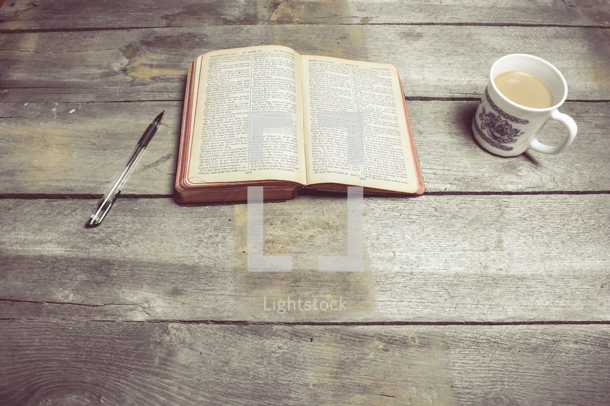 pen, opened Bible, and coffee mug 