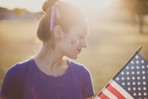 A young woman with USA face paint holding an American flag