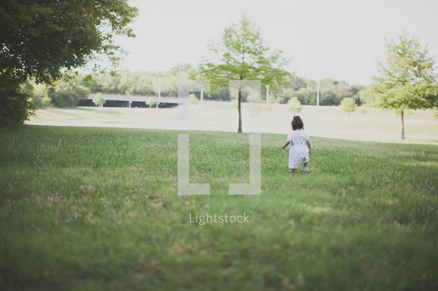 Girl walking in a grassy field outside.